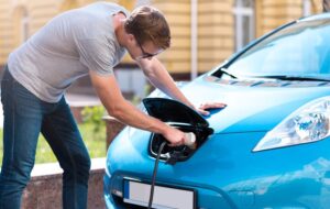 Man charging battery of eco car.
