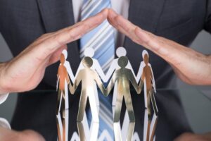 Two hands covering men-shaped papers