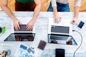 Two pair of hands side by side working on their own computer