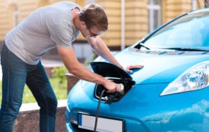 Man charging battery of eco car.