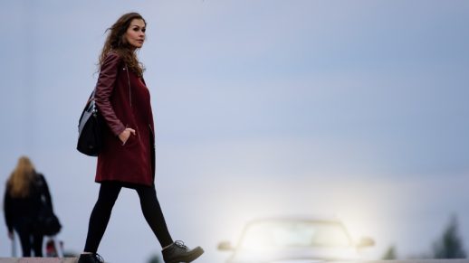 Woman crossing road dark bridge, car in background