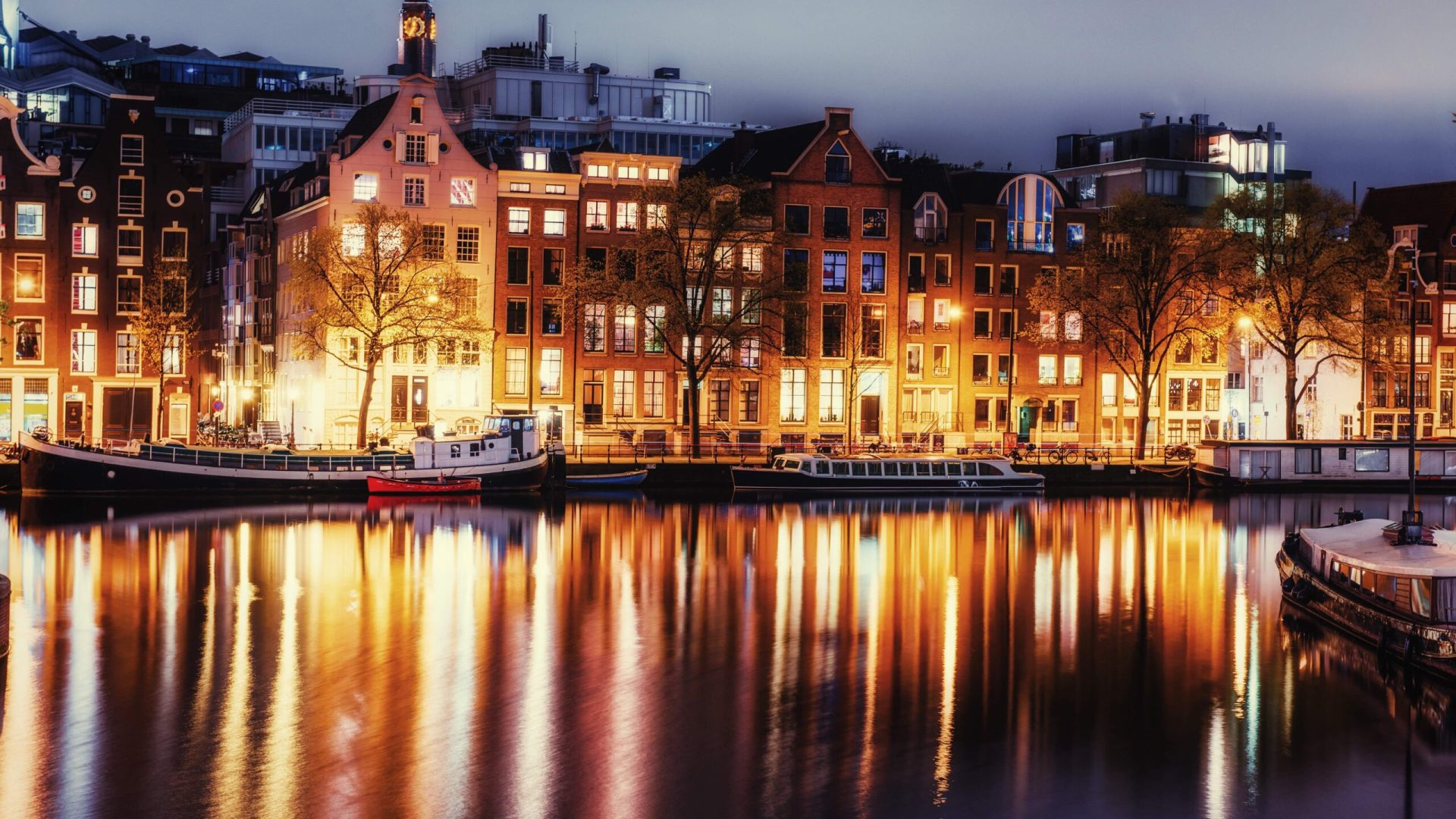 Beautiful night in Amsterdam with illuminated buildings and canal boats