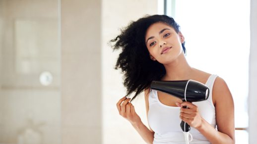 Shot of a young woman drying her hair in the bathroom
