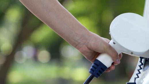 Cropped Hand Charging Car At Station