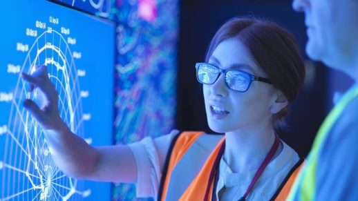 Female geologist with colleague studying graphical display of oil and gas bearing rock on screens