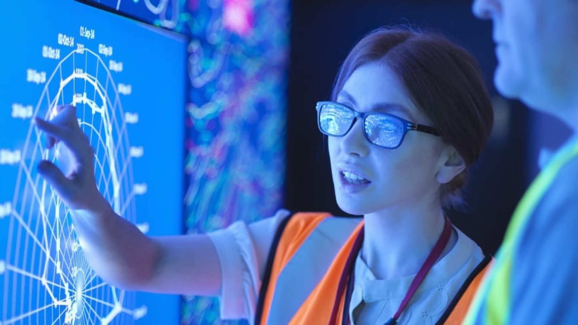 Female geologist with colleague studying graphical display of oil and gas bearing rock on screens