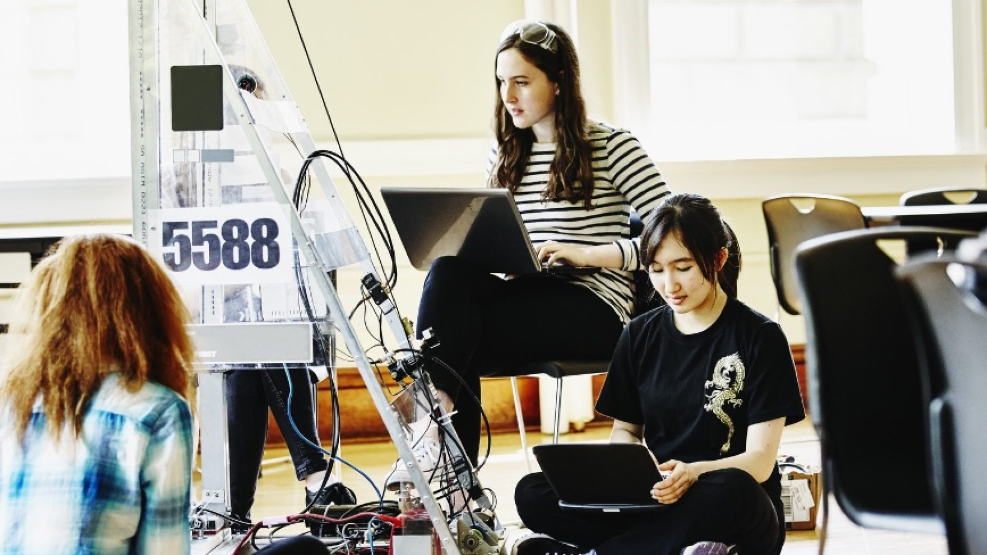 Female high school robotics team preparing robot for competition