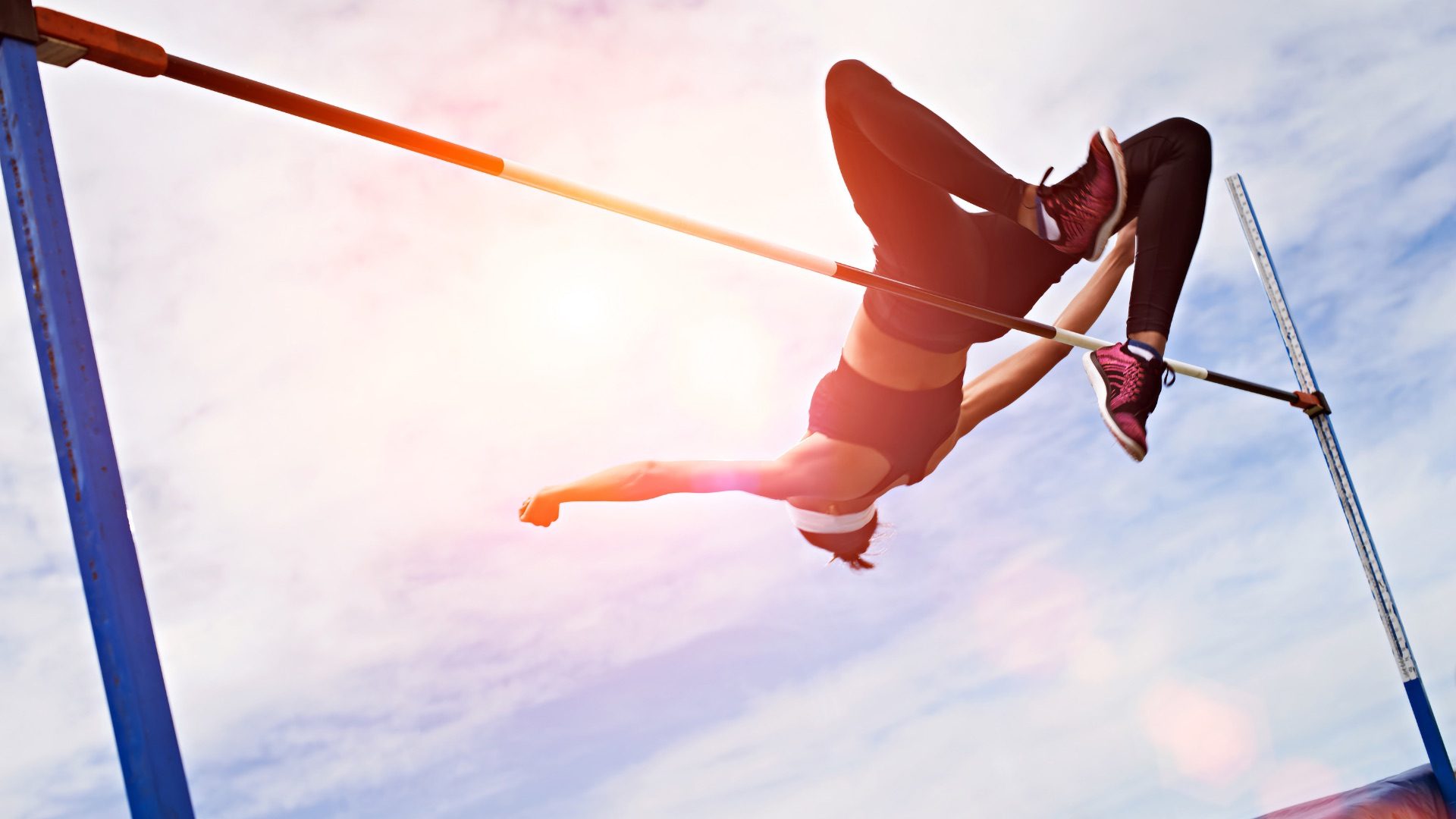 Shot of a young woman in mid air doing a high jump on a sports field