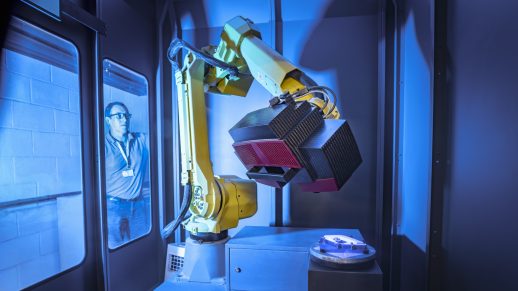 Operator watching robot scanning finished parts for quality control in an aerospace parts factory